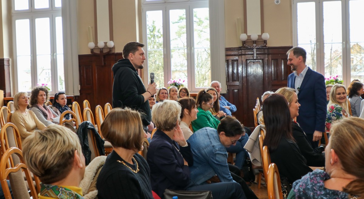 w sali siedzą uczestnicy wykładu. Męzczyzna stoi, zadaje pytanie.