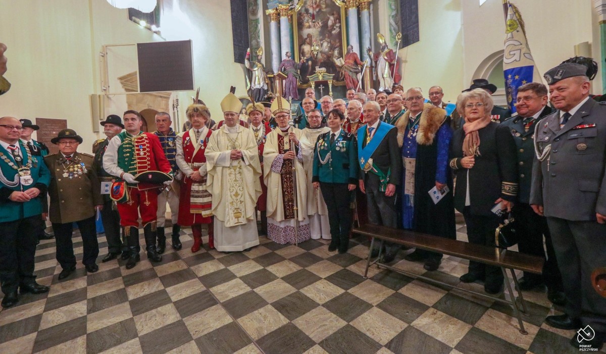 W kościele przed ołtarzem stoją bracia kurkowi przebrani w tradycyjne stroje, arcybiskup i księża