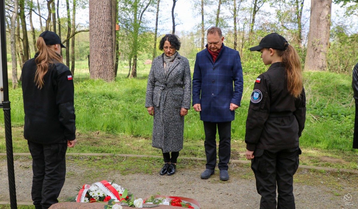 Starosta z wicestarostą pochyleni nad pomnikiem w parku.