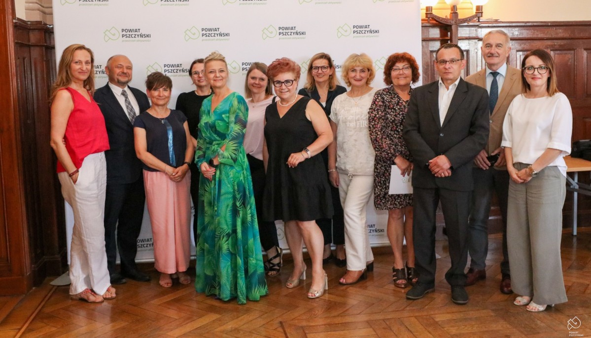 Przedstawiciele organizacji stoją w sali sesyjnej na współnym zdjęciu ze starostą