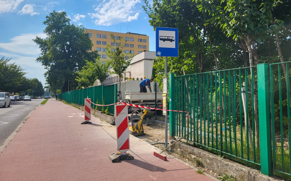 Ulica korfantego w Pszczynie, pachołki ustawione na ścieżce rowerowej, zielony płot, przy którym trwają roboty