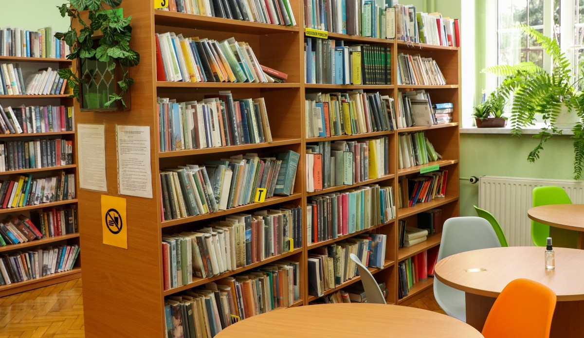 Biblioteka w I LO im. Bolesława Chrobrego. Na regałach stoją książki, obok ustawione stoły z krzesłami.