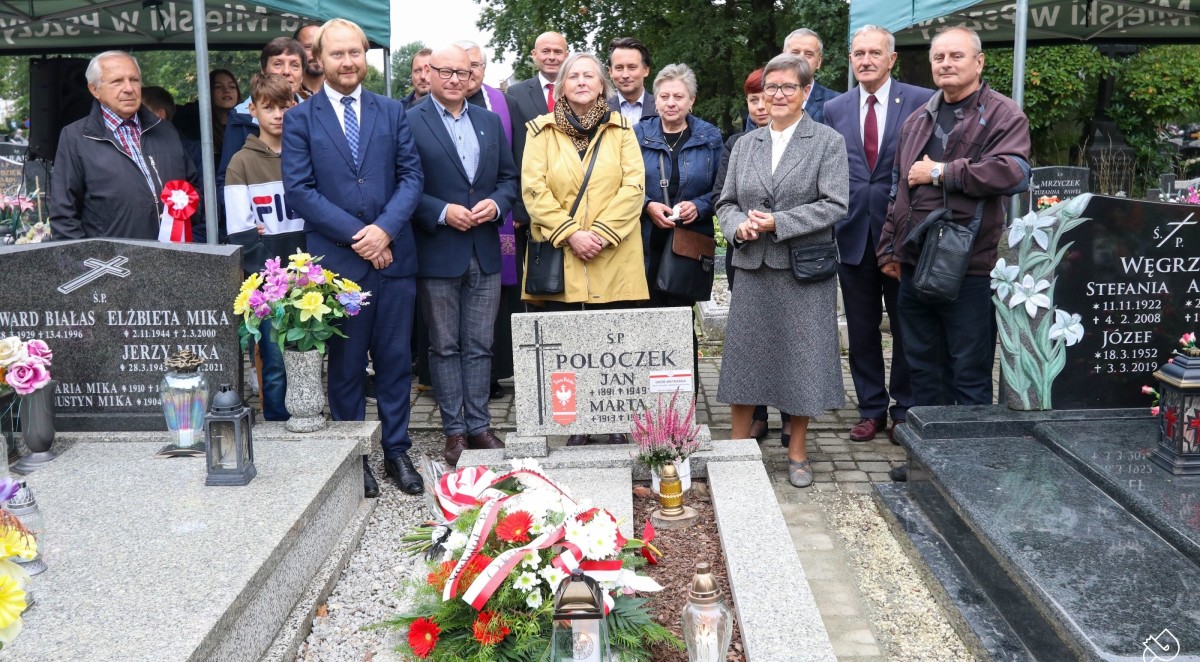 Grupa osób stoi przy oznaczonym grobie powstańca.
