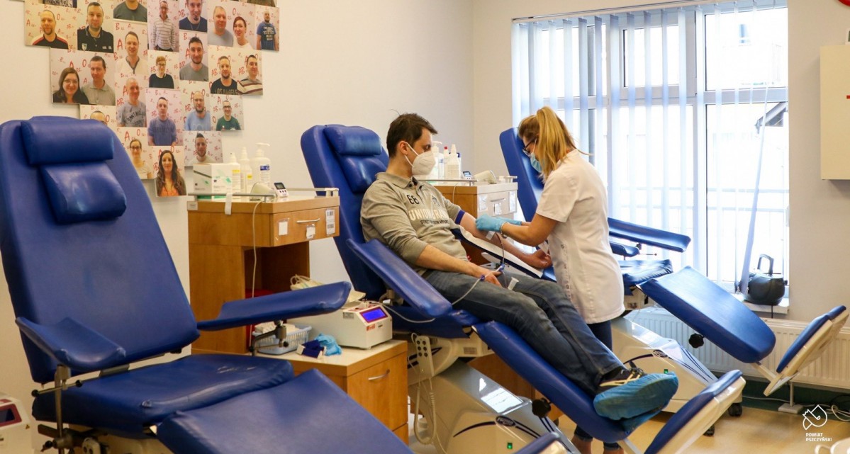 Wnętrze pszczyńskiej stacji krwiodawstwa. Trzy fotele, na środkowym siedzi mężczyzna, przy nim stoi pielęgniarka, która przygotowuje pobieranie krwi.