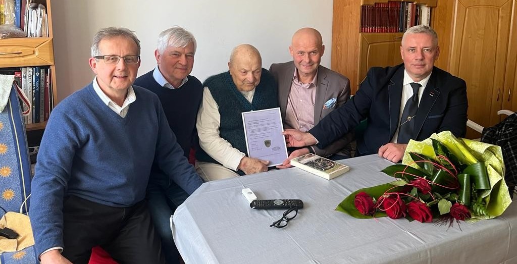 Na łóżku siedzą uczetsnicy pszczyńskiej delegacji oraz gen. Zdzisław Baszak