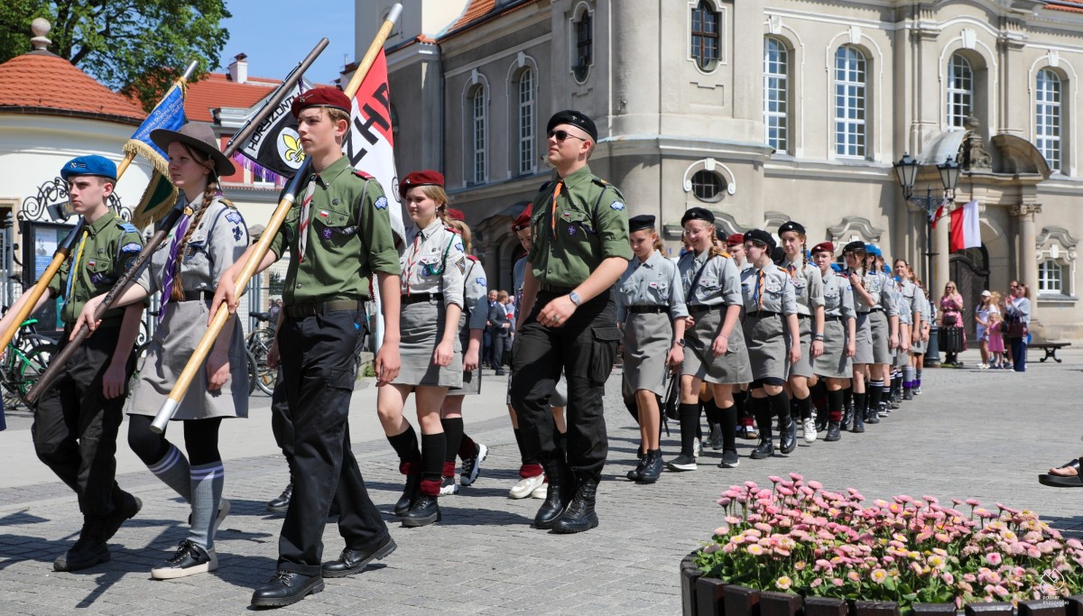 Harcerze idą w pochodzie przez pszczyński rynek.