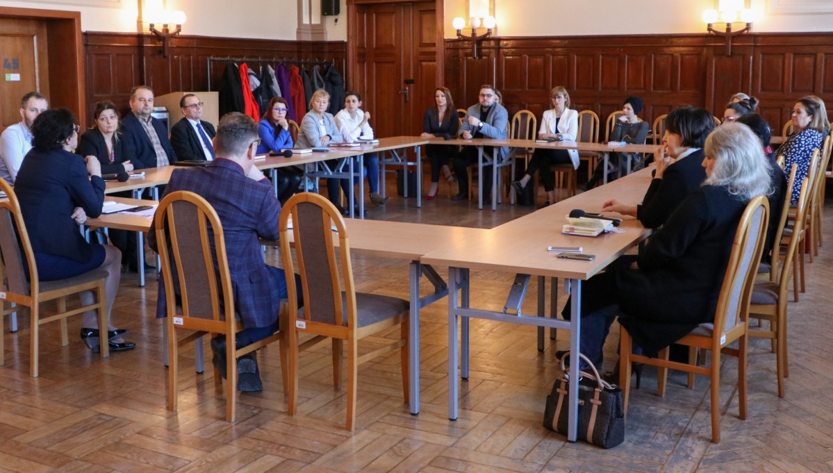 W dużej sali za stołami siedzą ludzie