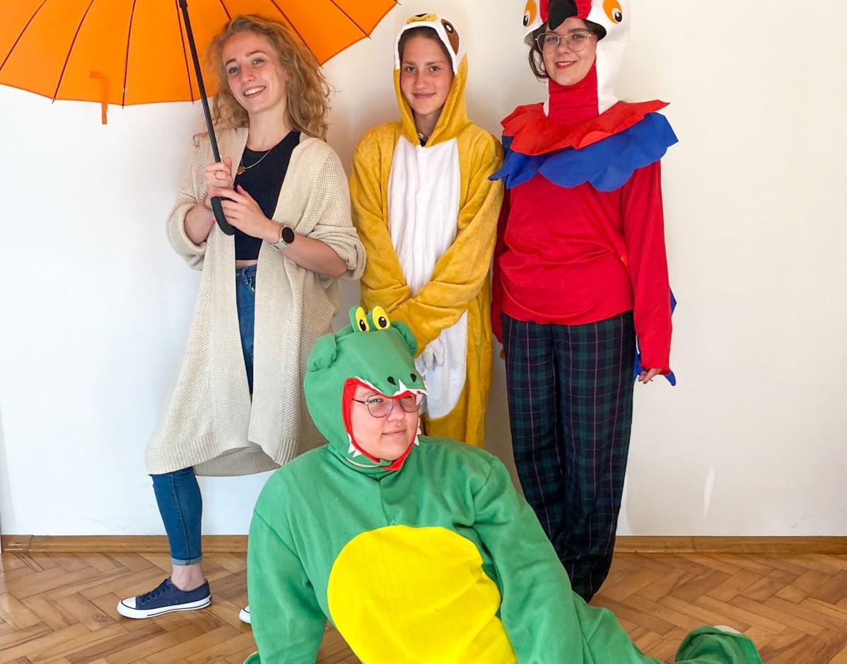 Grupa aktorek w strojach zwierząt, jedna trzyma parasol.