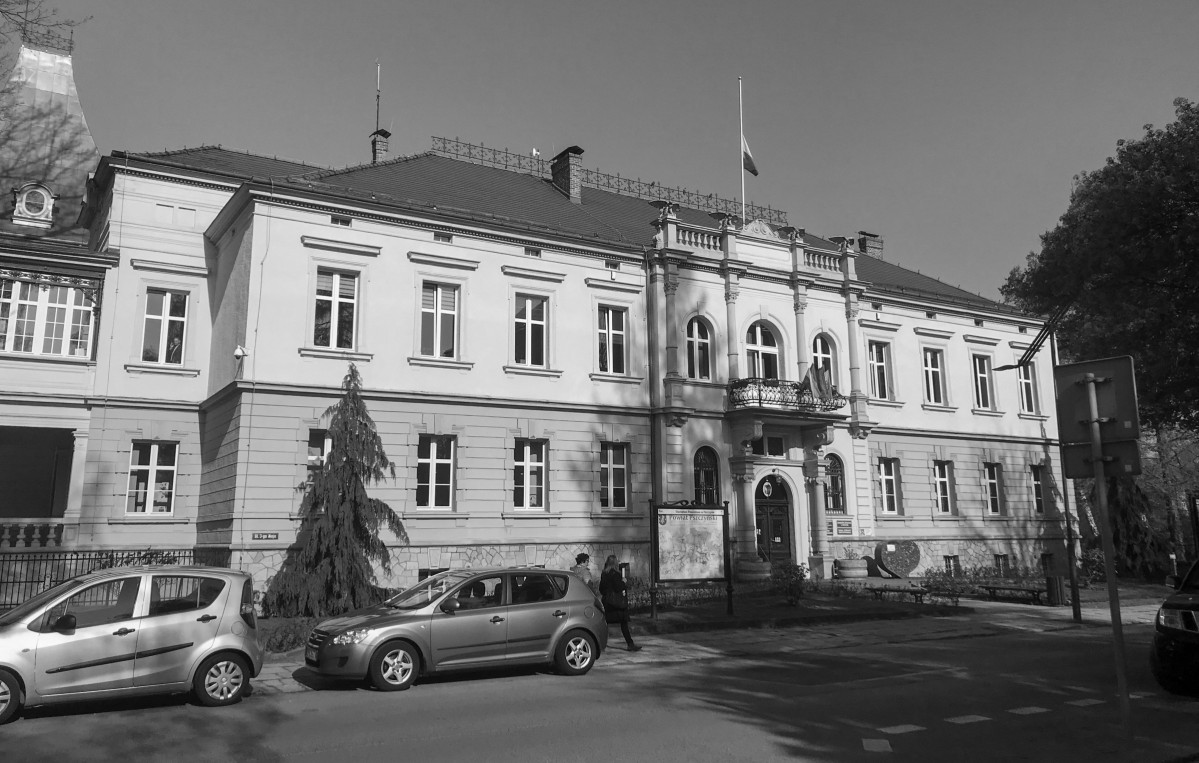 Czarno-białe zdjęcie starostwa, na budynku flaga Polski została opuszczona do połowy masztu.