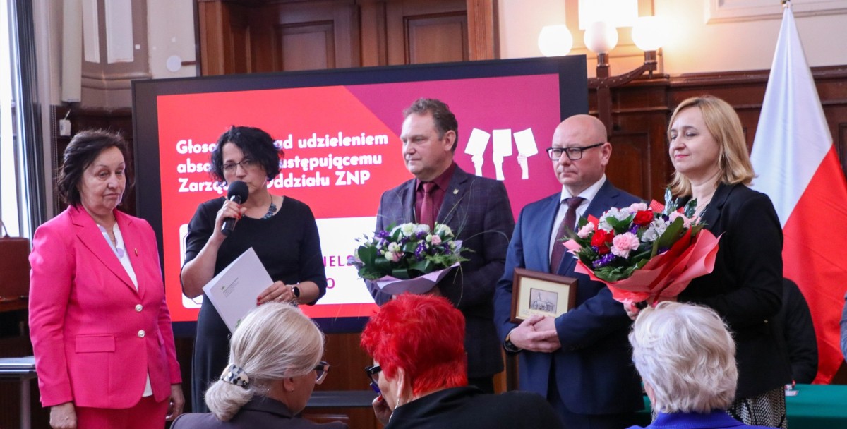 Alina Michalak stoi na środku sali sesyjnej starostwa wspólnie z samorządowcami