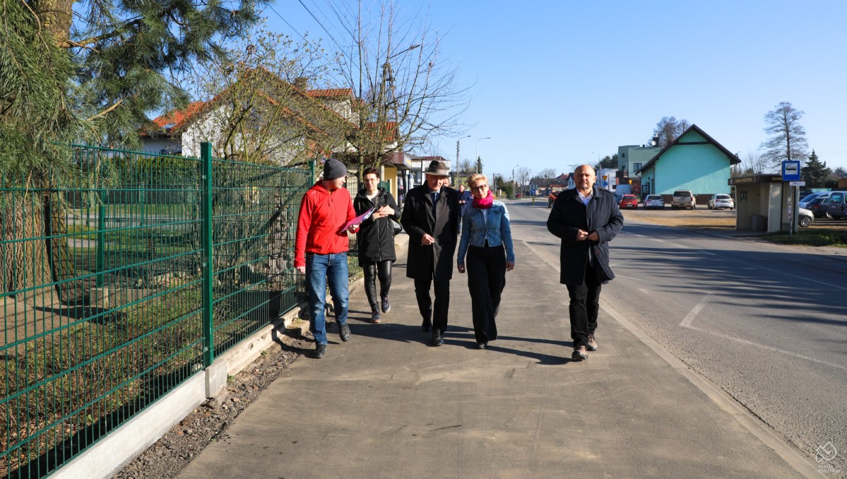 Samorządowcy, PZD i wykonawca idą wyremontowanym chodnikiem.