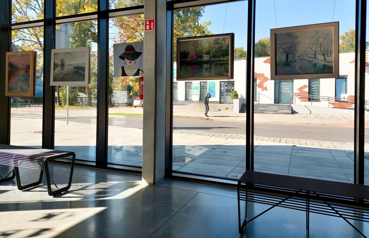 Obrazy powieszone w przeszklonych witrynach budynku Centrum Przesiadkowego.