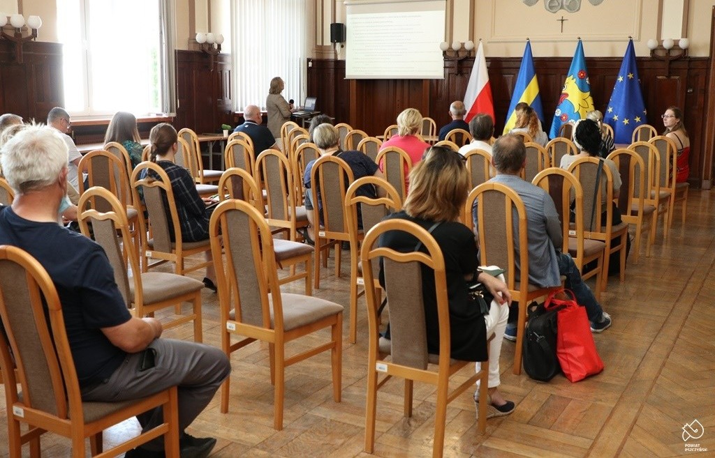 Na sali sesyjnej pszczyńskiego starostwa siedzą uczestnicy warsztatów. Wyświetlana jest prezentacja.