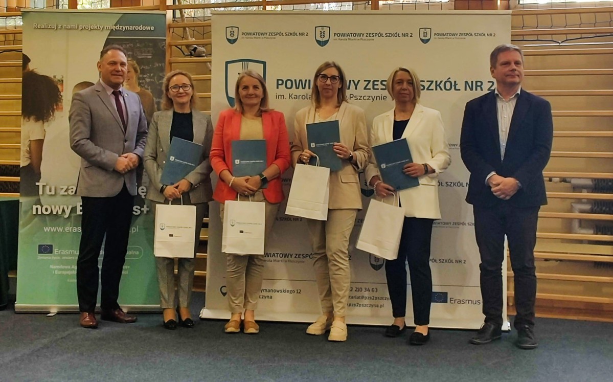 Grupa nauczycieli stoi w sali szkoły
