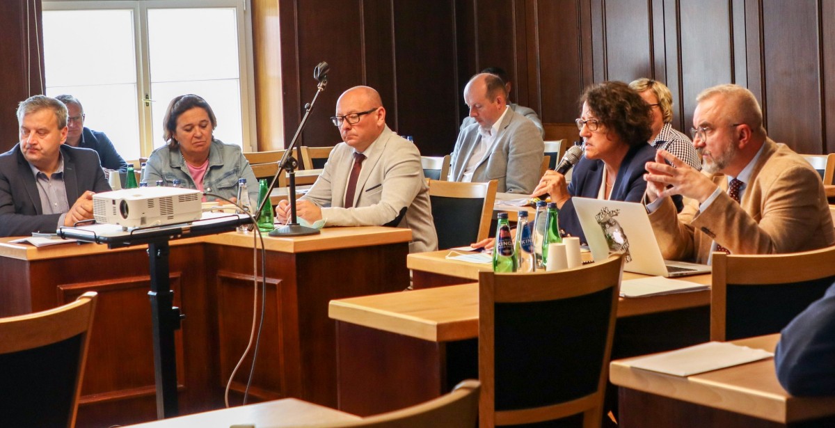 W sali sesyjnej ratusza trwa posiedzenie komisji. Za ławami radnych siedzą burmistrz, jego zastępcy, starosta i prezes spółki prowadzącej szpital.