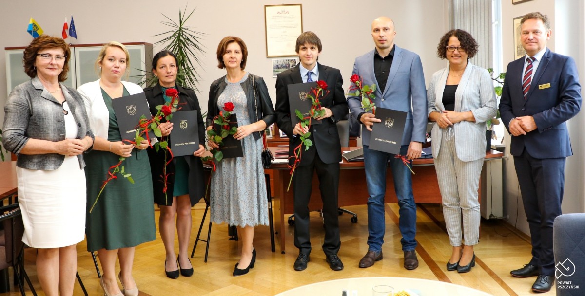 Pięcioro nauczycieli, którzy odebrali akty mianowania, starosta, wicestarosta i naczelnik wydziału oświaty stoją w gabinecie starosty. Nauczyciele trzymają czerwone róże.