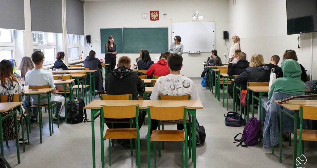 Uczniowie siedzą w klasie w ławkach