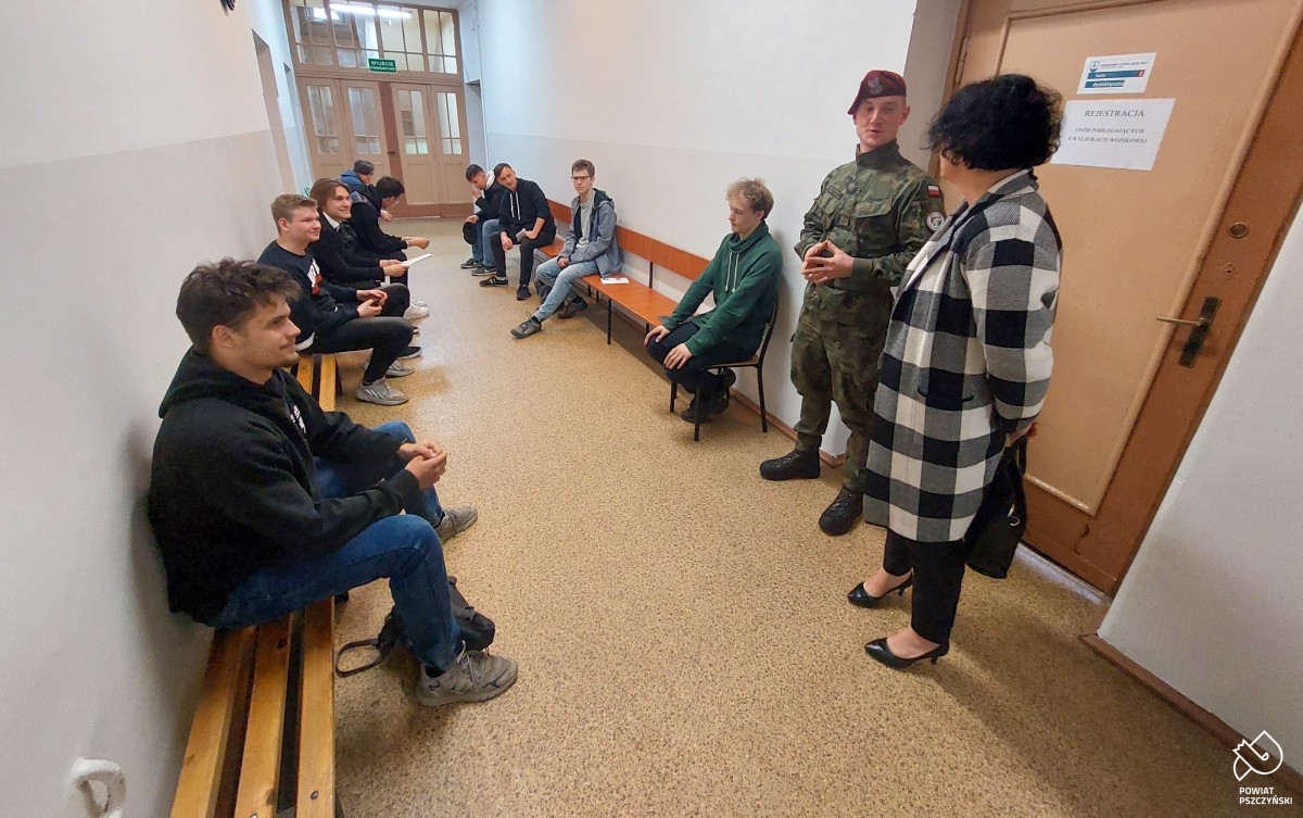 Starosta z wojskowym a na ławkach osoby, które otrzymały wezwanie.