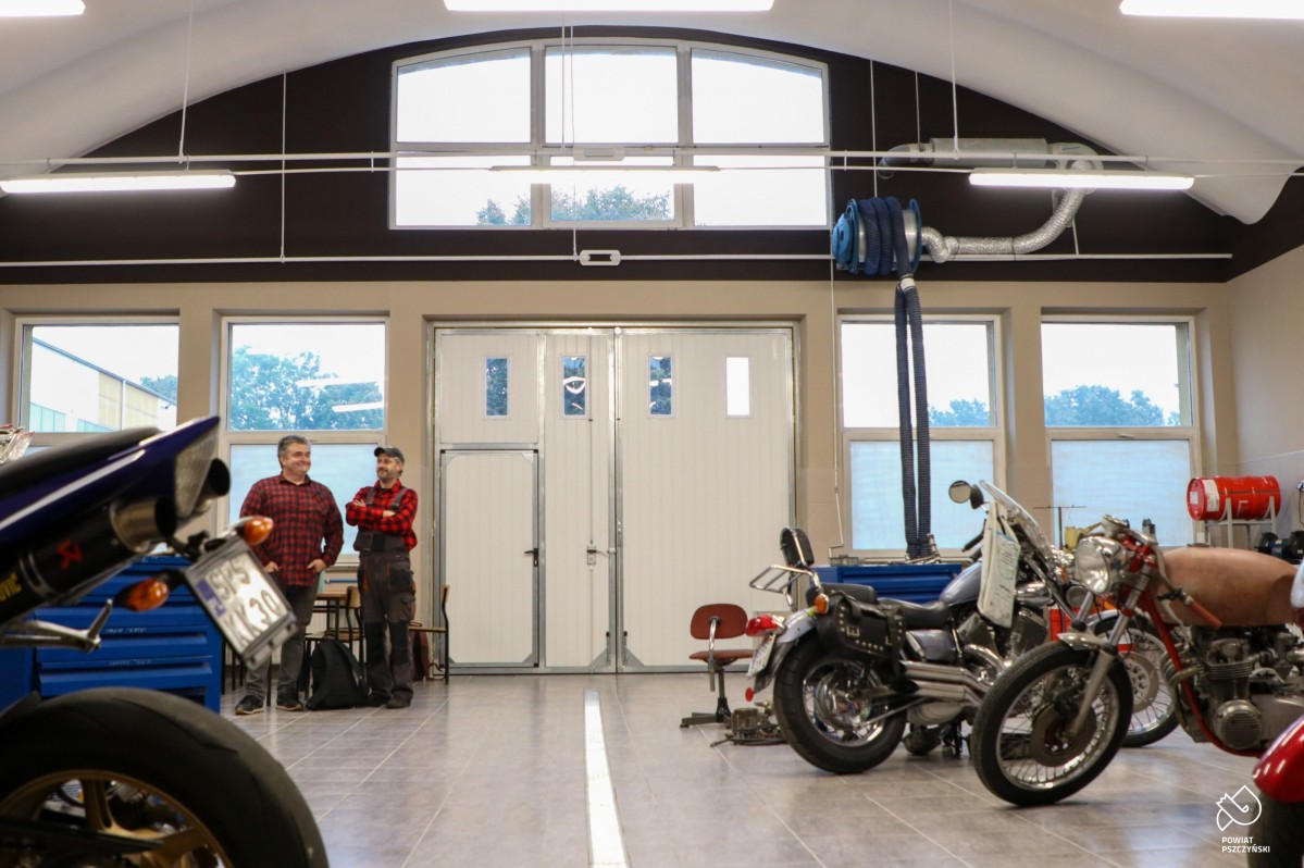 Wnętrze pracowni motoryzacyjnej duze pomieszczenie w którym stoją maszyny i motocykle