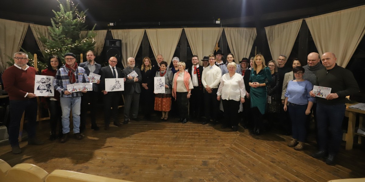 Uczetsnicy promocji stoją w altanie w pszczyńskim skansenie, w rękach trzymając publikację