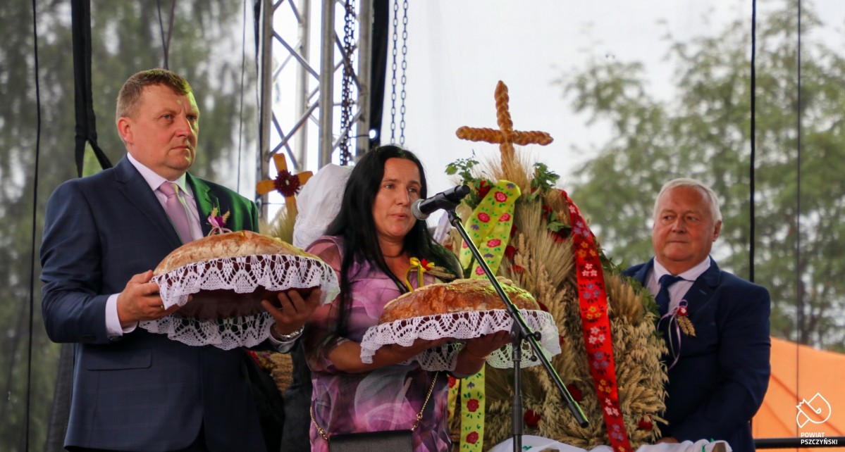 Starostowie dożynkowi trzymają chleb dozynkowy, stoją na scenie.