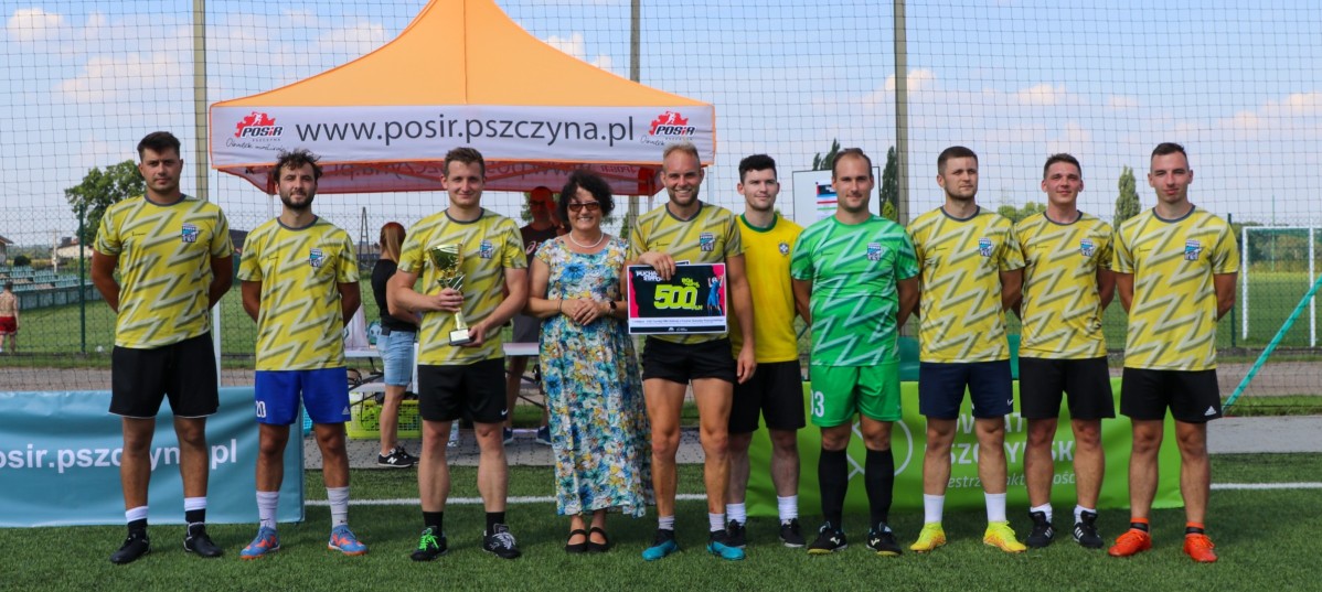 Dużyna z Bielska ubrana w żółto-niebieskie stroje stoi na murawie wspólnie ze starostą Barbarą Bandołą