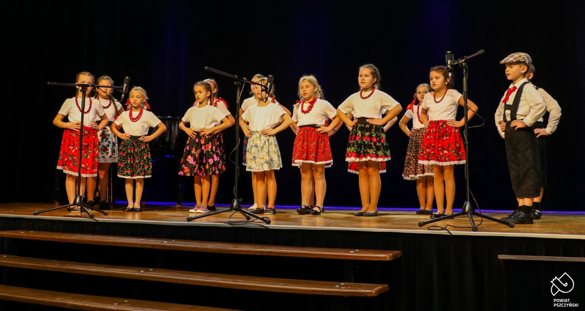 Zespół regionalny "Radość" występujący na scenie. Dzieci w strojach regionalnych.
