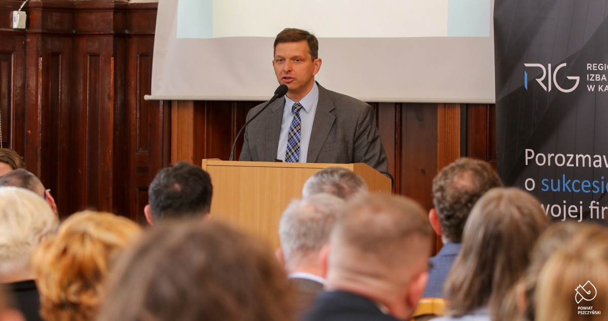 Marek Zuber podczas wykładu. Na sali sesyjnej na krzesłach w rzędach siedzą przedsiębiorcy.
