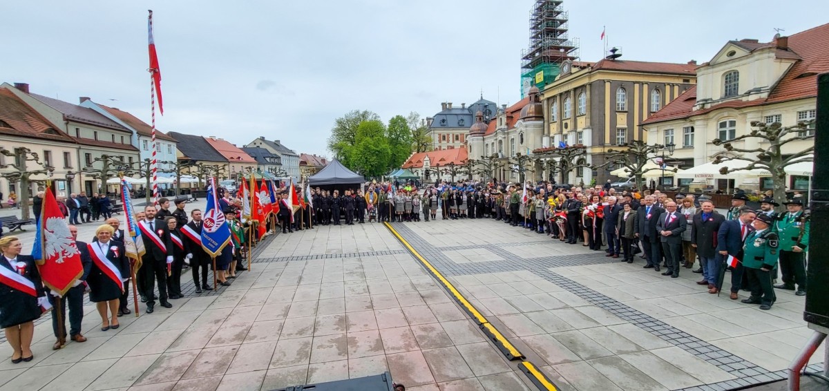 Na płycie pszczyńskiego rynku w półkolu stoją uczestnicy rocznicy uchwalenia konstutucji 3 Maja