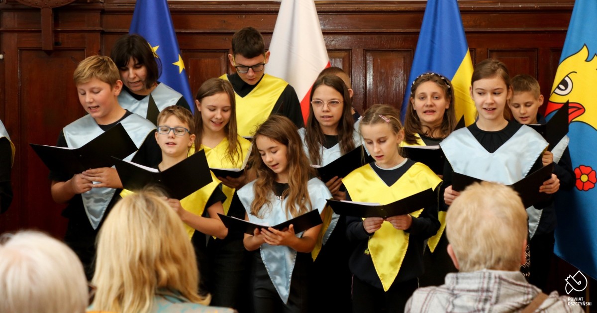 Uczniowie śpiewający przed publiczością.