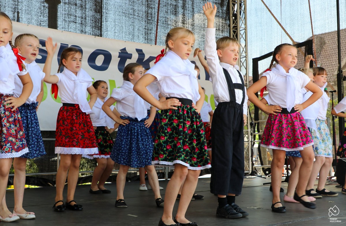 Dzieci w regionalnych strojach tańczące na scenie.