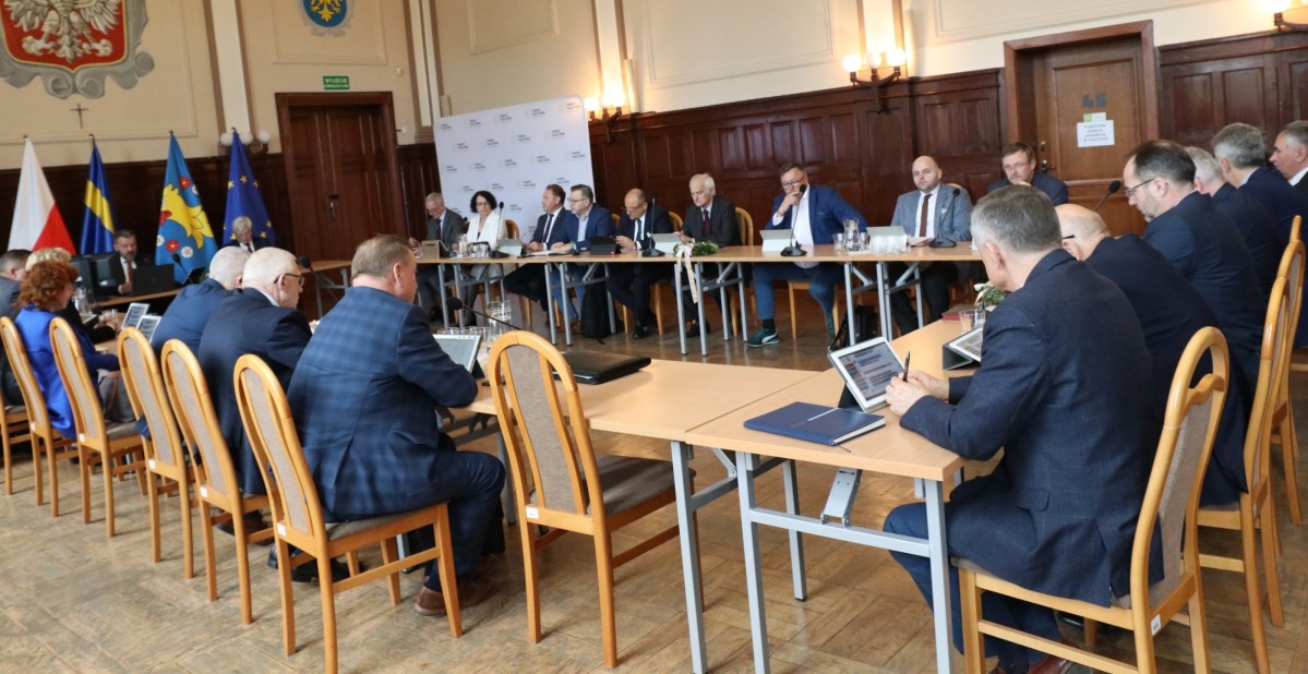 Trwa sesja Rady Powiatu. Radni siedzą przy stołach.