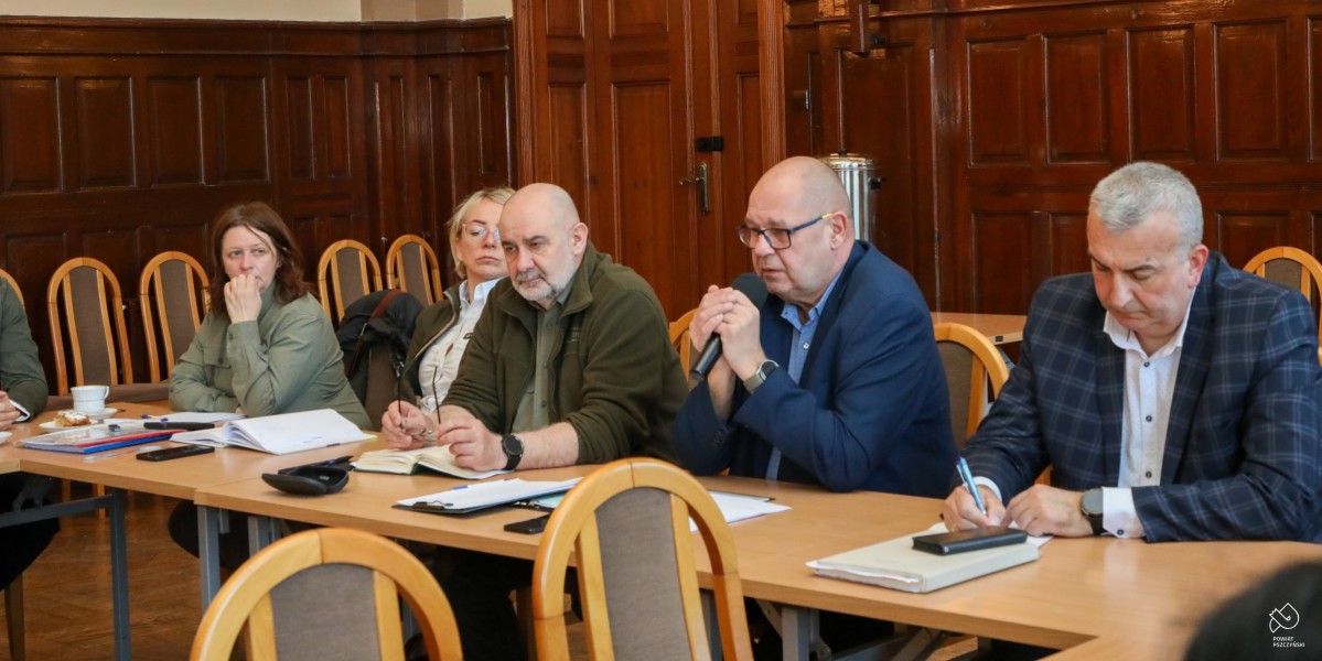 W sali sesyjnej za stołami siedzą osoby. Do mikrofonu mówi powiatowy lekarz weterynarii