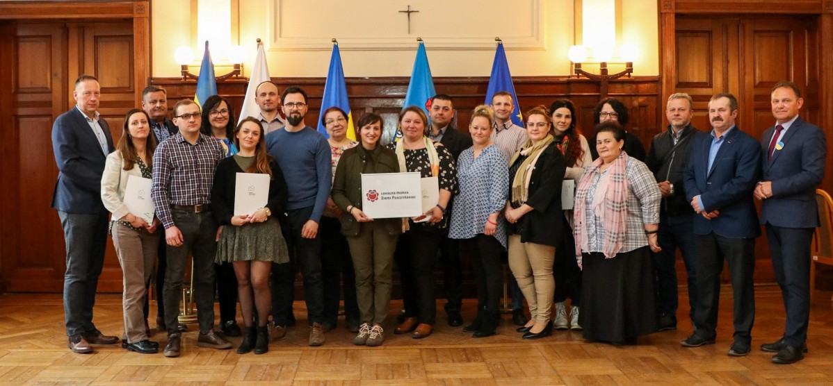Grupa osób stoi w sali sesyjnej starostwa powiatowego.
