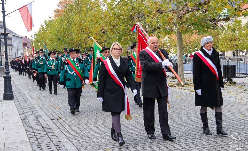 Poczty sztandarowe w przemarszu po rynku.