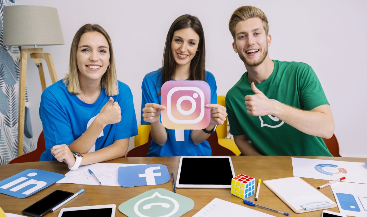 Trzy osoby trzymają elementy graficzne social mediów.