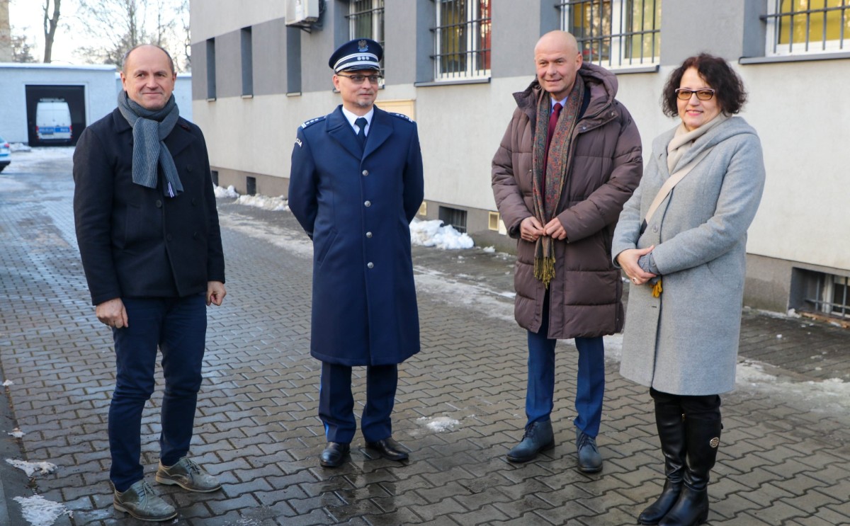 Trzej mężczyźni i kobieta stoja przed budynkiem komendy policji. Są to komendant powiatowy, sekretarz i przewodniczący Rady Gminy Suszec oraz starosta pszczyńska.