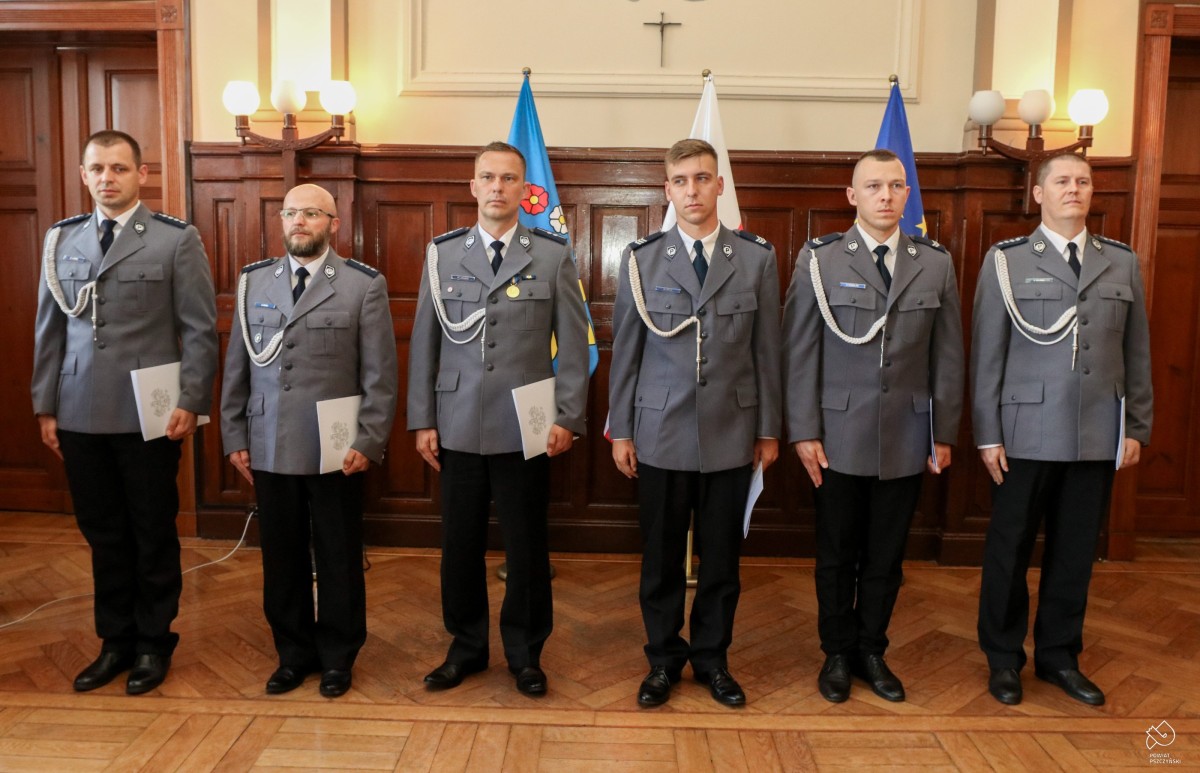 Policjanci ustawieni w szeregu w sali sesyjnej.