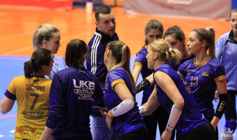 Siatkarki drużyny UKS Centrum Pszczyna wraz z trenerem w budynku hali sportowej.