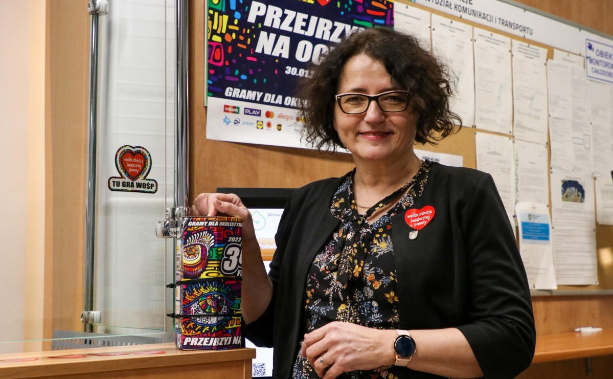 Starosta Barbara Bandoła stoi na korytarzu starostwa przy stacjonarnej puszce Wielkiej Orkiestry Świątecznej Pomocy