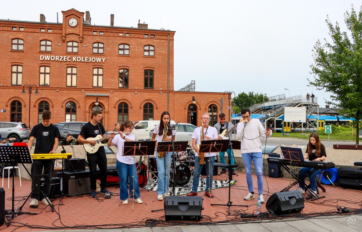 Muzycy występują przed dworcem.