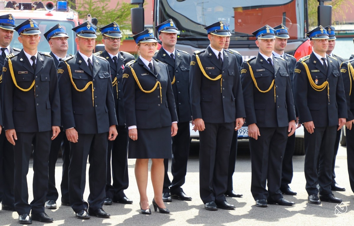 Strażacy w uroczystych mundurach ustawienie w szeregu na baczność.