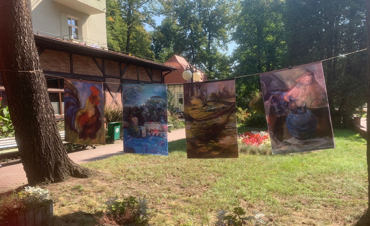 W penerze na sznurze wiszą wydrukowane na tkaninach obrazy