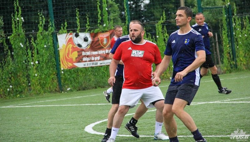 Piłkarze grający w piłkę nożną na boisku Orlik podczas deszczu.