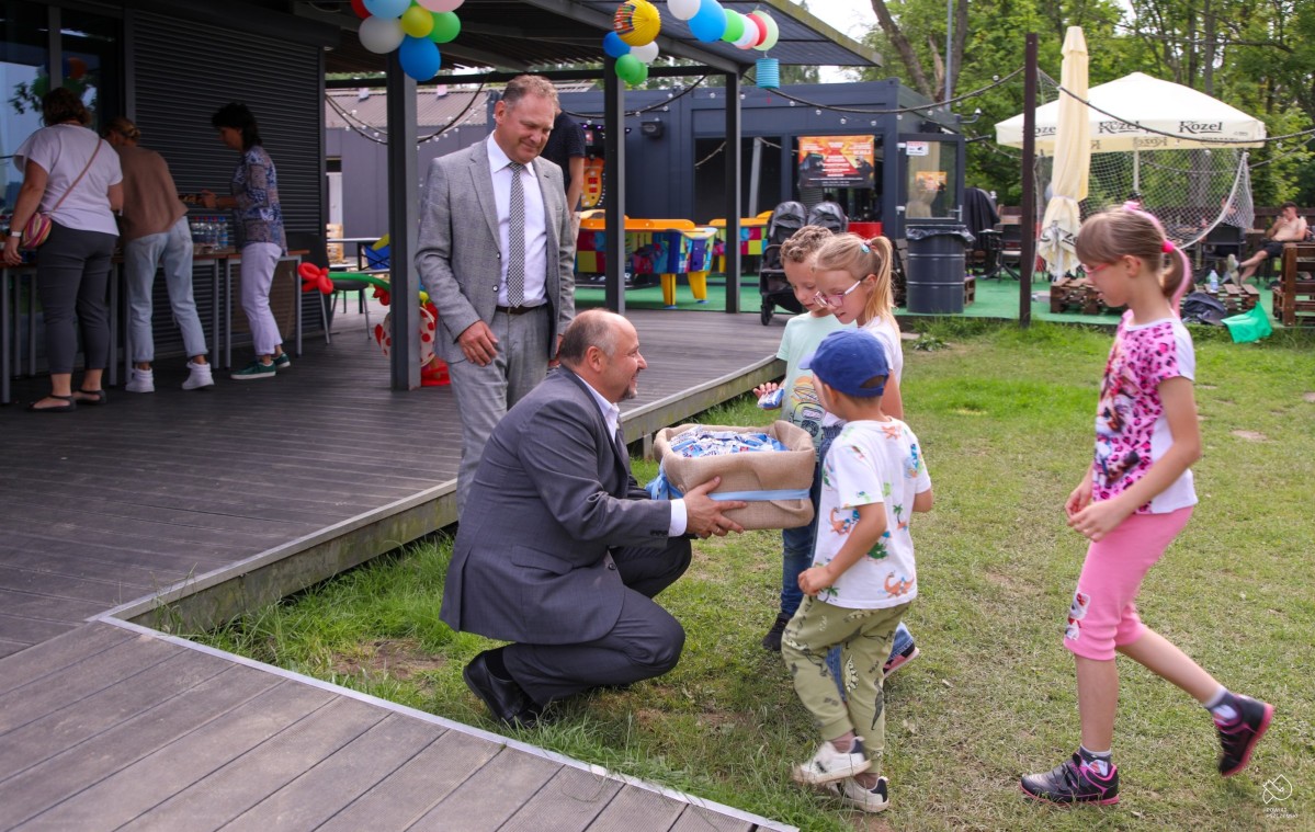 Starosta i wicestarosta częstuja dzieci batonikami