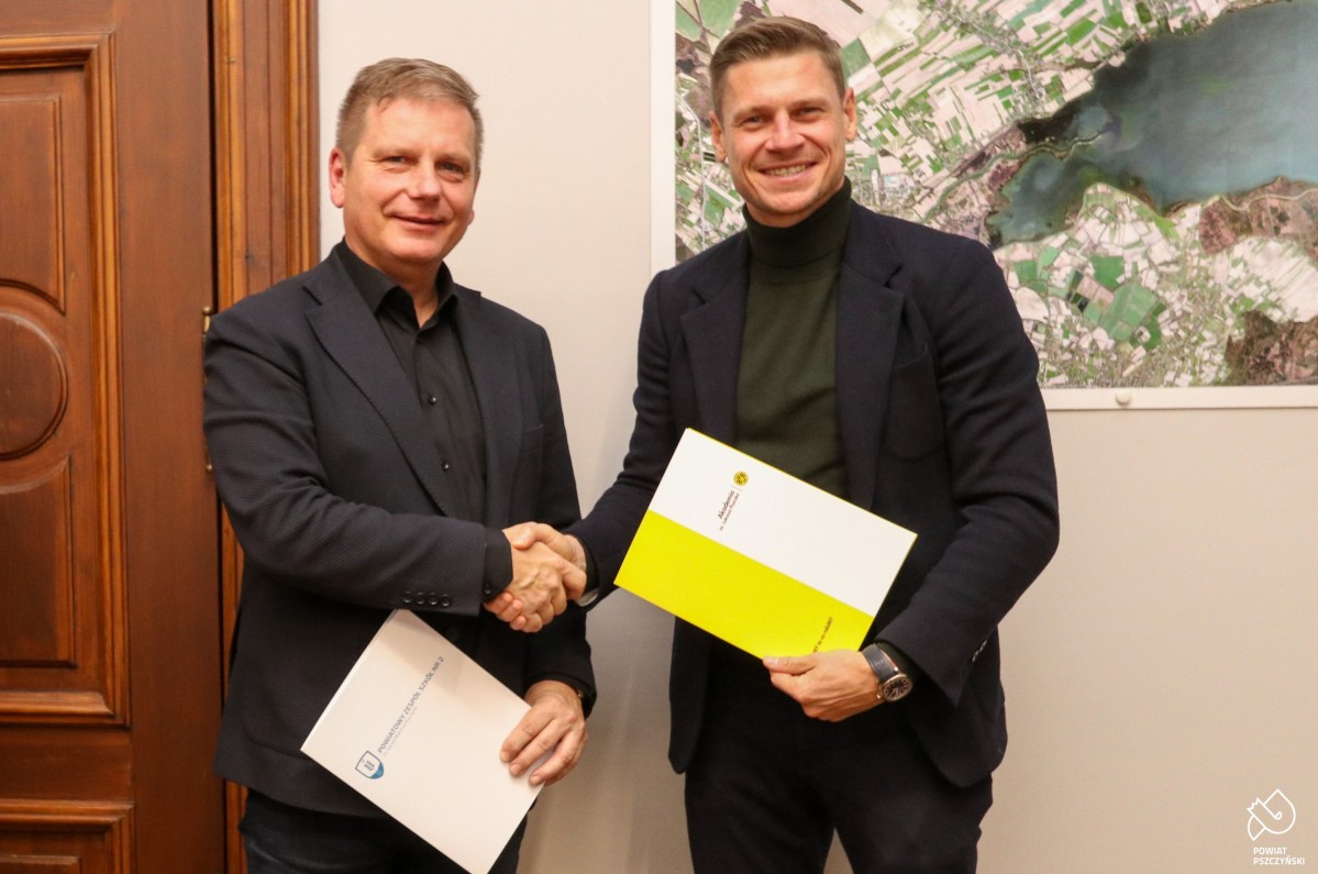 Łukasz Piszcze i dyrektor szkoły podający sobie dłonie po podpisaniu umowy.