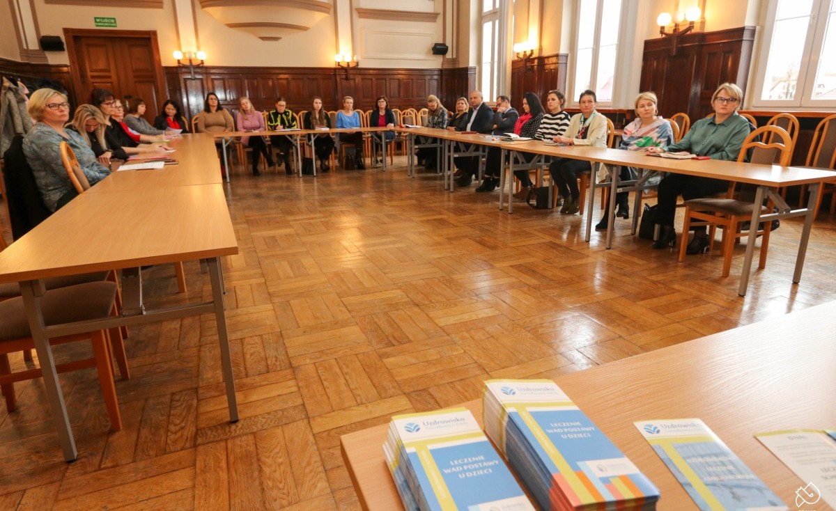Grupa osób siedzi za stołem w sali sesyjnej starostwa