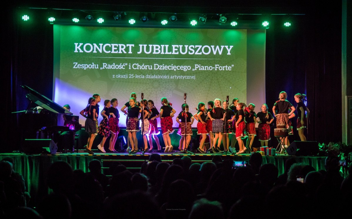 Dzieci w kolorowych strojach regionalnych występują na scenie.