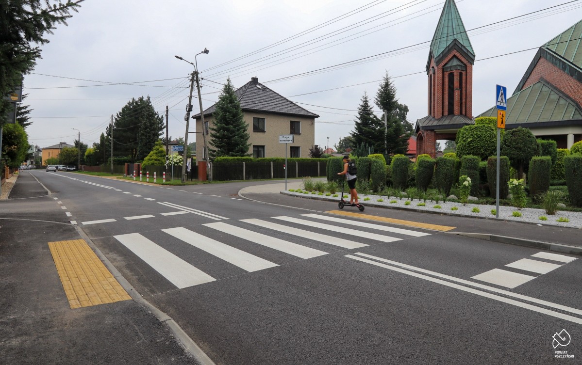 Przebudowana droga, jadący na hulajnodze chłopiec. Przejście dla pieszych