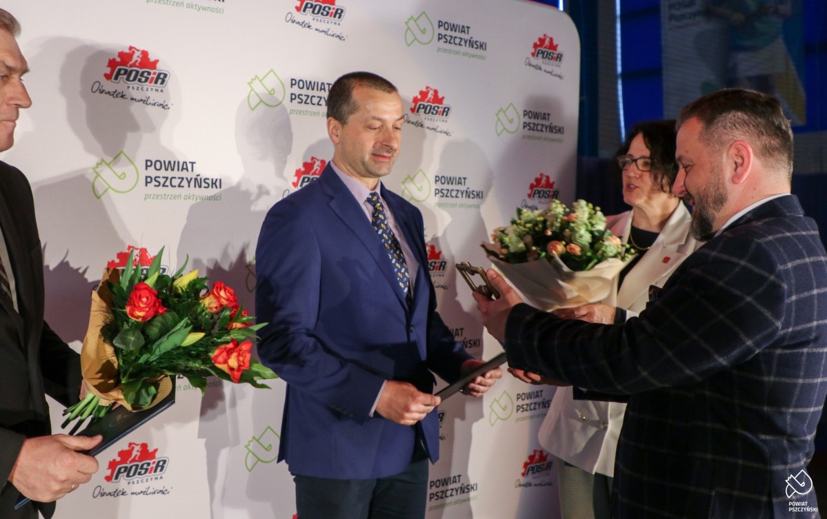 Paweł Sadza wręcza statuetkę Żubra prezesowi MUKS Gilus na scenie.